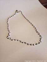 Full view of the necklace showing the pearl and silver link chain arrangement.