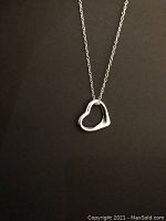Heart pendant hanging on the chain against a black background, showing size and shape clearly