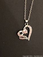 Close-up of silver-tone heart pendant with pink stones on necklace chain