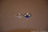 Rings set, placed side by side on brown background, showing blue stone ring and band ring.