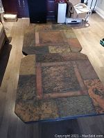 Full view of two slate end tables placed together forming a coffee table, showing geometric tile pattern tops in earth tone colors.