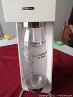 Front view of white SodaStream Source soda maker with attached clear plastic bottle