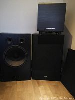 Front view of two Genexxa GX 1500 speakers and one Cerwin Vega subwoofer stacked on right speaker.