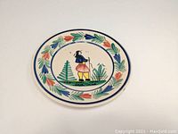 Top view of round plate showing central Breton man figure and floral border pattern.