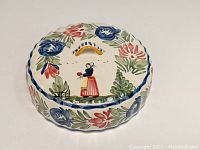 Top view of the Quimper pottery lid with colorful floral and Breton woman painting