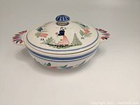 Front view of covered serving bowl showing the lid with the Breton woman and handles.