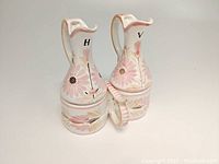 Two Quimper pottery cruet bottles with floral motifs in their ceramic carrier.