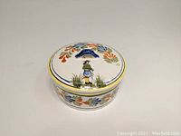 Circular pottery box with lid, top view showing Breton man motif and floral decorations