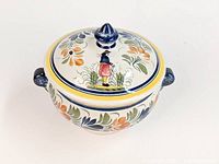 Full view of the footed covered serving bowl showing the lid with the Breton man motif and floral decoration.