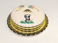 Overall view of the cheese/butter dish with lid showing the Breton man and woman motif and scalloped design.