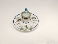 Front view of the white ceramic finger candlestick holder with painted floral patterns and centered candle socket.