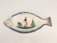Top view of fish shaped serving platter showing the hand-painted Breton woman and foliage design.