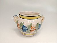 Front view of the round handled pot with floral motif showing two decorative handles and colorful flower pattern.