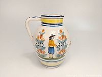 Side view of the jug showing the hand-painted Breton man motif and floral design with handle visible.