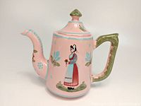Front and side view of pink Quimper coffee pot with hand-painted Breton girl motif and floral decoration, green handle and lid knob.