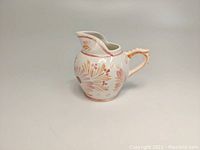 Front angle view of HenRiot Quimper pottery creamer showing the handle and floral design