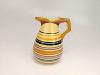 Front view of HenRiot Quimper pottery pitcher showing colorful horizontal bands and angular handle.
