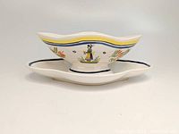 Side view of the HenRiot Quimper pottery sauce/gravy bowl with affixed underplate, showing Breton girl motif and hand-painted floral decoration.
