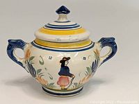 Front view of sugar bowl showing Breton man motif and floral decorations.