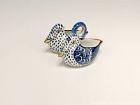 Front angle of hand-painted double swan ceramic salt dip or condiment server in blue and white with gold on beaks.
