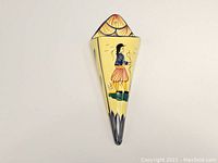 Front view of triangular ceramic wall pocket vase with painted Breton man motif and yellow background.