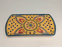 Top view of rectangular platter showing the colorful geometric and floral design featuring yellow, red, and blue colors.