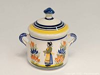 Front view of ceramic sugar bowl with lid showing the hand-painted Breton woman and floral design.