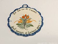 Front view of round scalloped HenRiot Quimper wall plaque with floral design and French inscription.