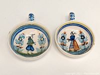 Top view of the pair of round Quimper pottery teacups with painted Breton figures inside.