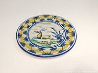 Top view showing the full front surface of the plate with central stag and surrounding yellow and blue motifs.