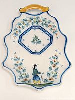Front view of HenRiot Quimper pottery croissant plate showing scalloped edges, floral decoration, central recessed well, and Breton man motif