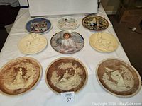 Image showing nine collector's plates arranged on a white surface, including colorful Hamilton Collection plates, ivory alabaster plates, and sepia-toned decorative plates.