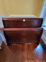 Full view of queen-size sleigh bed showing headboard and footboard with wood finish.