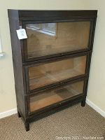 Three-section barrister bookcase assembled with dark wood finish and closed glass-front doors