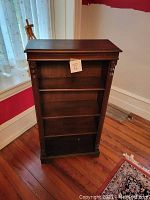 Front view of the antique 4-shelf wooden bookcase showing carved columns and open shelves.