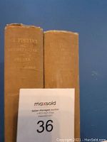 Photo of two hardcover books titled 'The Puritan in Holland, England and America' showing their spines and covers side by side against a blue background with auction number card number 36.