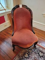 Front view of 19th century ladies mahogany chair with burnt orange upholstery showing carved frame and padded seat and back.