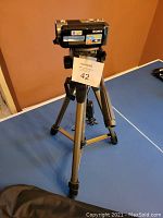Sony Handycam mounted on Dynex tripod shown on a table with lot tag.