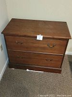 Front view of the mid-century 2-drawer wooden lateral file cabinet showing brass handles and wood finish.
