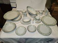 Full display of Noritake Spring Meadow china including various plates, bowls, cups, saucers, and serving pieces arranged on table.