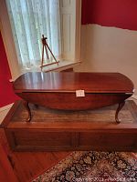 Coffee table closed with drop-leaf sides down, showing the elongated oval shape and cabriole legs.