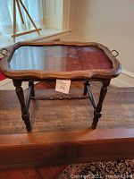 Side view of antique Butler's tea table showing turned legs and wooden structure with serving tray on top.