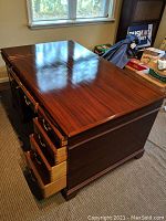 Full view of the mahogany partner's desk showing the polished top surface and drawers pulled out on one side.