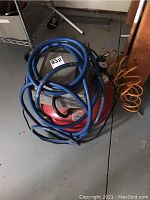 Porter Cable red and grey electric air compressor with blue hose coiled around it and orange hose attached.