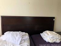 Frontal view of dark brown panel headboard with bedding on frame