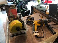 Overview of the Dewalt hammer drill next to a plastic container holding various circular drill bits and accessories.