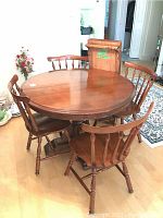 Dining table and 4 chairs set with round table extended with two leafs in background.