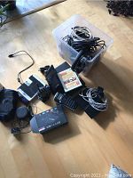 Full view of electronic items including two MXQ Pro OTT TV boxes, cables, headsets, label maker, CDs, and a remote.