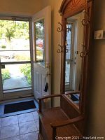 Overall view of oak bench and mirror in entryway showing full piece and context