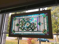 Front view of the stained glass panel showing central medallion, scrollwork, wood frame and hanging chain